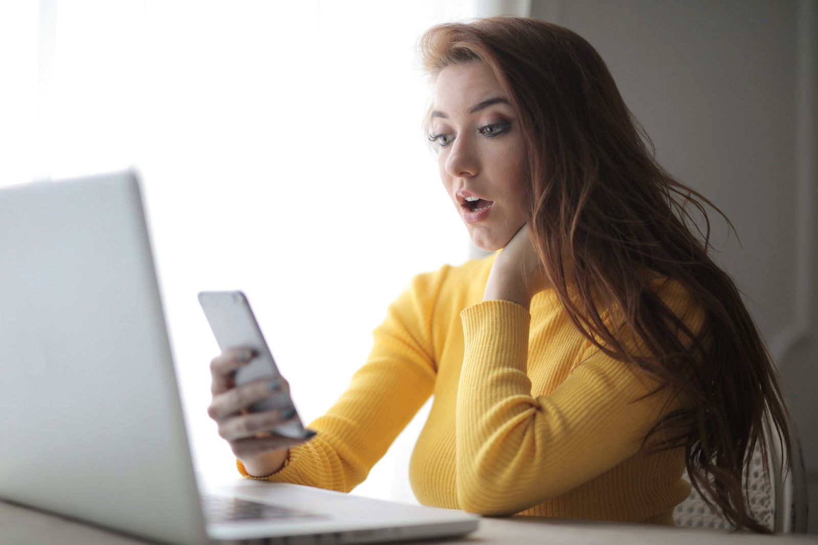 Canva Woman in Yellow Turtleneck Sweater Holding Phone Sitting Beside Laptop